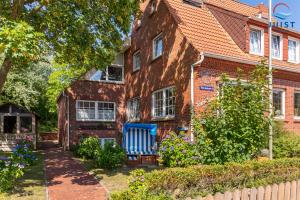 een bakstenen huis met een blauwe bank ervoor bij Töwerland Zimmer 2 in Juist