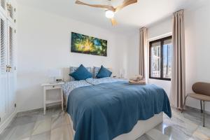a white bedroom with a blue bed and a chair at La Riviera in La Cala de Mijas +16 photos
