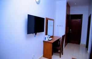 a room with a desk and a television on a wall at Greenyard Beach Hotel in Entebbe