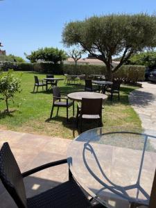 a glass table with chairs and tables in a park at Hôtel Tamaris in Le Lavandou