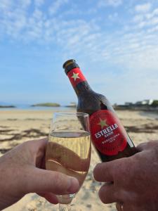 a person holding a bottle of beer on the beach at The Caravan in Anglesey