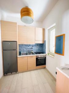 Una cocina con gabinetes de madera y un refrigerador de acero inoxidable. en San Leone Mare House, en San Leone