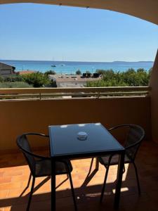 a table and chairs on a balcony with a view of the ocean at Hôtel Tamaris in Le Lavandou
