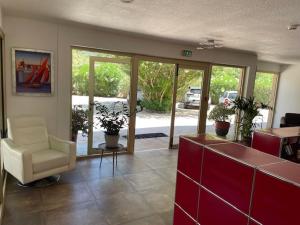 a living room with a couch and a chair and glass doors at Hôtel Tamaris in Le Lavandou