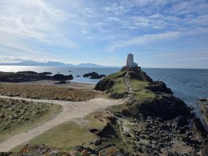a lighthouse on a rocky island in the ocean at The Caravan in Anglesey