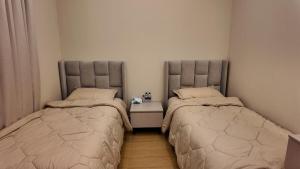 a bedroom with two beds and a nightstand between them at كمباوند ماربيلا الكورنيش شقة in Ar Rākah +40 photos