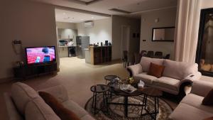 a living room with a couch and a tv at كمباوند ماربيلا الكورنيش شقة in Ar Rākah