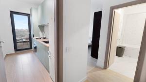 een keuken met witte muren en een deur naar een kamer bij Sarah Home in Boekarest