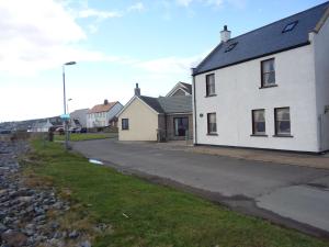 una casa blanca al lado de una calle en Seashore House en Johnshaven