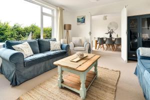 a living room with a blue couch and a table at Cornish house 5 min drive to beach in Falmouth