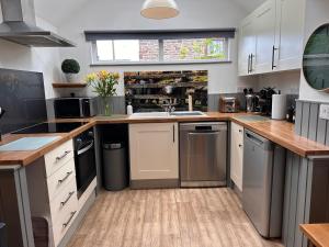 eine Küche mit weißen Schränken und einer Spüle in der Unterkunft Charming cosy cottage near the Lake District in Penrith