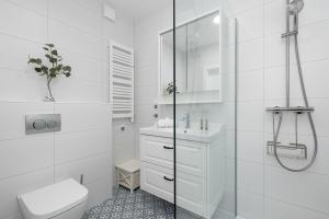 a white bathroom with a toilet and a sink at Urokliwy Apartament z Ogródkiem 150 m od Plaży Parking Międzywodzie by Noclegi Renters in Międzywodzie