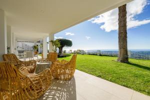 eine Gruppe von Stühlen auf einer Terrasse mit Meerblick in der Unterkunft Villa Los Arcos - Panoramic Breathtaking Views in Mijas