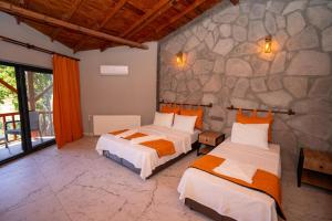a bedroom with two beds and a stone wall at Sokakağzı Otel & Beach in Ayvacık