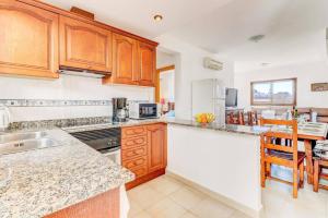 a kitchen with wooden cabinets and a counter top at Villa Mar Egos by Villa Plus in Cacla D'or