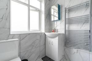 ein weißes Badezimmer mit Waschbecken und Fenster in der Unterkunft NEW Spacious House 6 Bedrooms 4Bathrooms 10 Guests in Romford