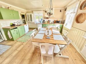 a kitchen with green cabinets and a wooden table and chairs at Family-friendly countryside house close to lake in Skärås