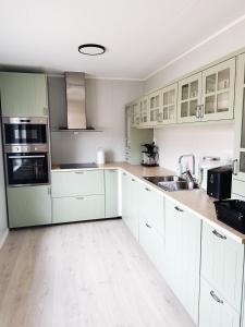 a white kitchen with white cabinets and appliances at Svartbakken Rooms in Vardø +16 photos