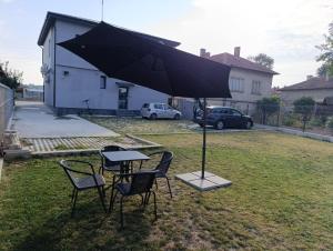 a table and chairs under an umbrella in a yard at Glavinitsa Luxury Suites, Главиница in Glavinitsa