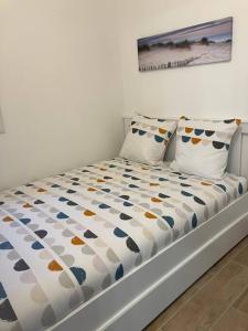 a bed in a white room with two pillows at Joli appartement côté plages in Sète