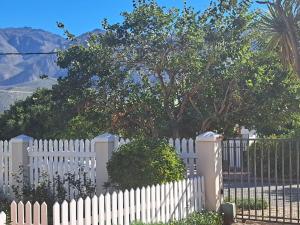 a white picket fence with a tree behind it at Fig Tree in Montagu +4 photos