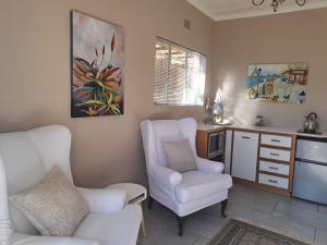 a living room with two white chairs and a kitchen at Fig Tree in Montagu