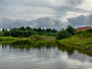a view of a river with a house and trees at Jäneda Safari Puhkemajad in Kõrveküla