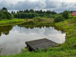 a small river with a wooden dock in the middle at Jäneda Safari Puhkemajad in Kõrveküla