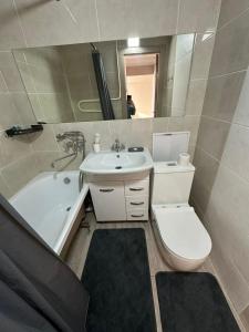 Un baño con inodoro, lavabo y bañera. en Apartment on Protozanova 21, en Öskemen