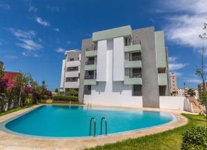 a building with a swimming pool in front of a building at SunRose appartement, Luxueux, sécurisée, piscine, Wi-FI, Pool et parking in El Jadida