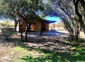 a small house in the middle of a field with trees at Lala Panzi in Ghanzi