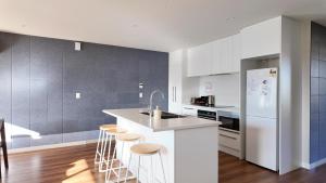 a kitchen with white appliances and a counter with stools at Tekapo Aunt Susan Holiday House in Lake Tekapo