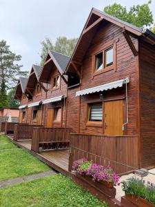 a wooden house with a fence and flowers at Domki Pod Dębami in Pobierowo