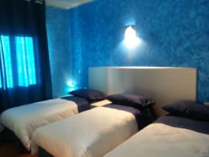 Habitación con 4 camas en una habitación con paredes azules. en Fenix, en Fontanafredda