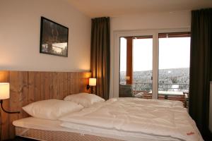 a bed in a hotel room with a large window at UplandParcs Residence Winterberg in Winterberg