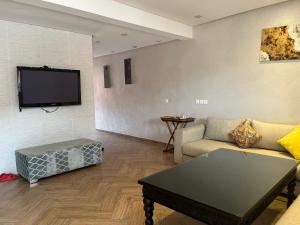 a living room with a couch and a flat screen tv at Duplex Imiouaddar in Imi Ouaddar