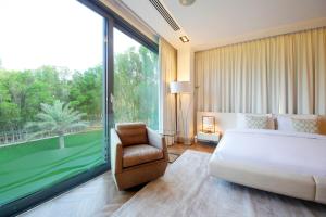 a bedroom with a bed and a chair and a large window at Luxurious Overwater Villa Escape on Nurai Island in Abu Dhabi