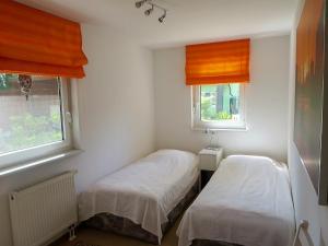 2 łóżka w małym pokoju z 2 oknami w obiekcie Ferienhaus Schillo w mieście Rangsdorf