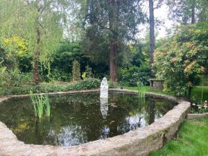 a fountain in a pond in a garden at Appartement dans un parc arboré privé in Bégard