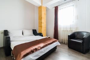 a bedroom with a bed and a black chair at Hotel Restaurant Imperial in Sighişoara