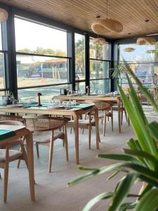 un ristorante con tavoli e sedie in legno e finestre di Sokakağzı Otel & Beach a Ayvacık