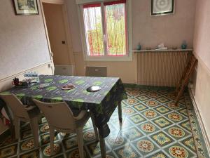 a dining room with a table and chairs on a tile floor at une détente à la campagne in Chierry