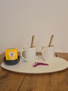 drei Kaffeetassen auf einem Teller auf einem Holztisch in der Unterkunft le rêve suspendu in Le Mans + 2 Fotos