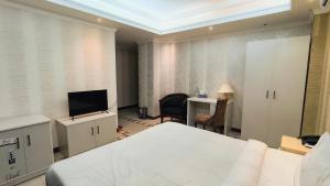 1 dormitorio con 1 cama, TV y escritorio en Sea Shell Palace, en Dhaka