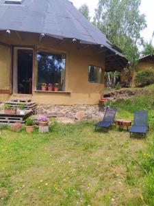 a house with two chairs in front of it at Okrągła Chata in Morzyszów