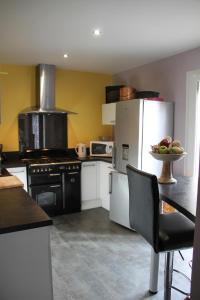 een keuken met een koelkast en een tafel met een fruitschaal bij le parc des combes in Saint-Beauzile