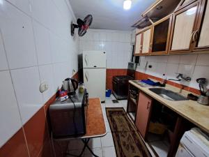 a small kitchen with a sink and a refrigerator at Royal ALEXANDRIA APARTMENT GOOD NIGHT in Al ‘Āmirīyah +32 photos