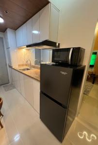 a kitchen with a microwave and a refrigerator at Skyview 2BR at Grass in Manila