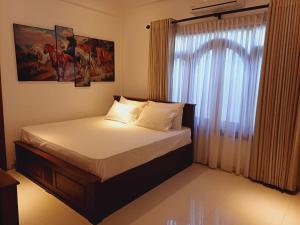a bedroom with a bed and a window with curtains at JarushanInnHotel in Jaffna