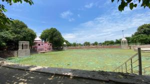 a large field in front of a pink building at Agnihotri Tourism Centre in Machhrehta